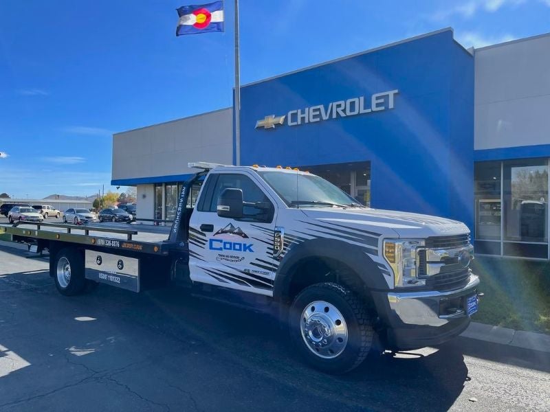 Cook Towing Service flatbed tow truck parked outside Cook Chevrolet in Northwest Colorado